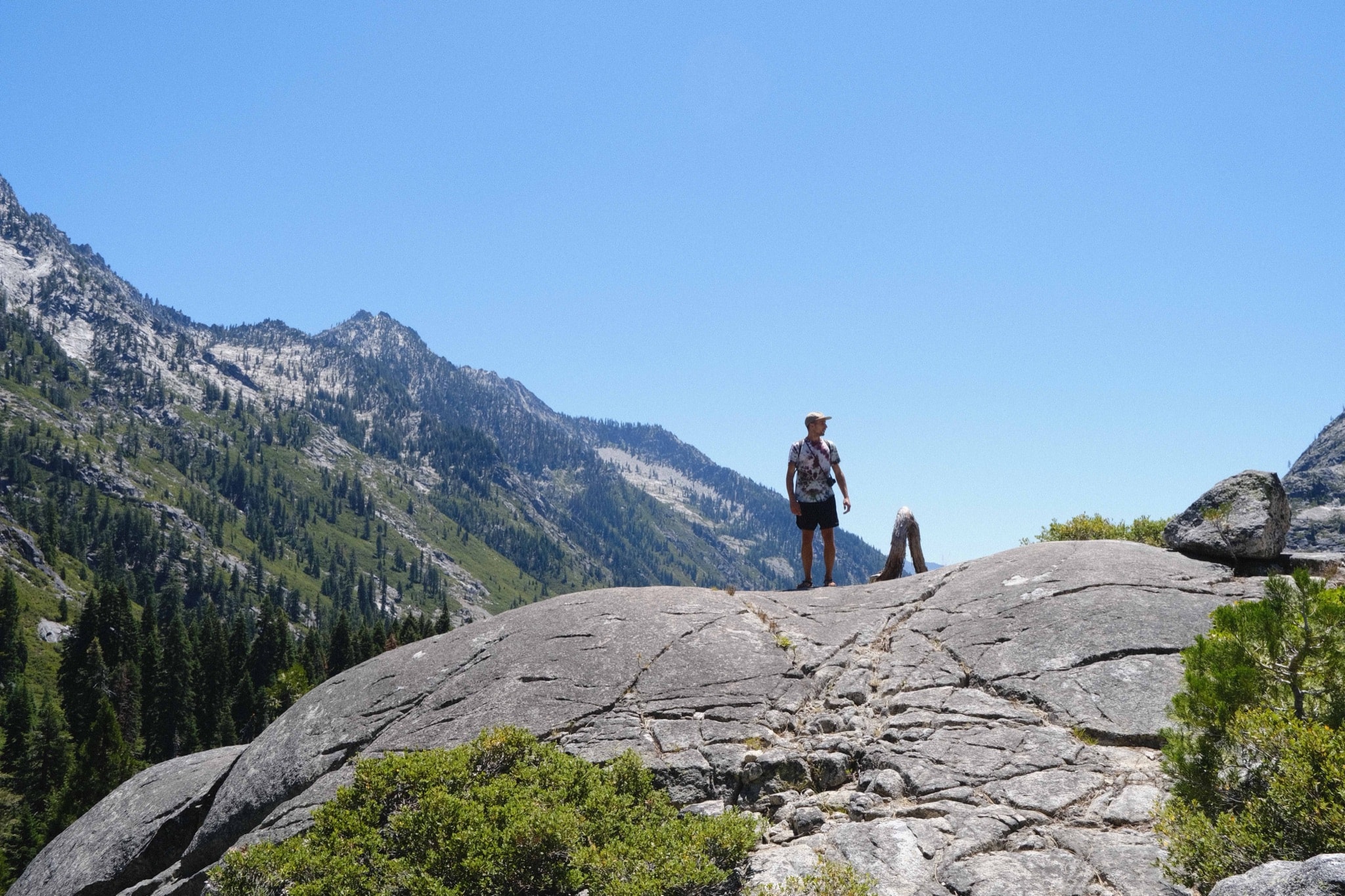Eli standing on a granite dome above a mountain valley